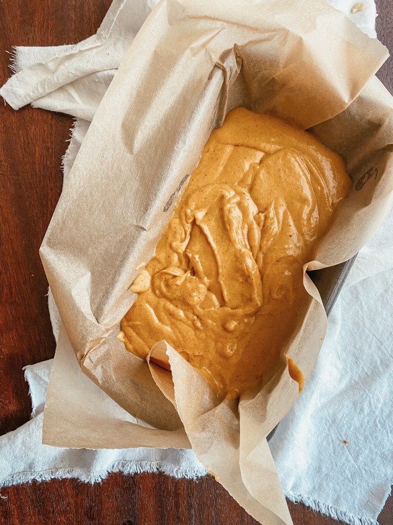 pumpkin bread batter in a loaf pan with parchment paper