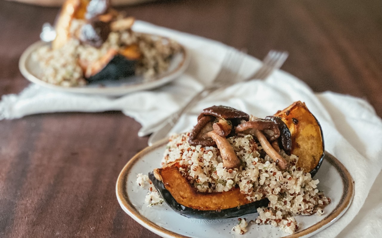 Herb roasted acorn squash with quinoa and buttery mushrooms on a small plate and white napkin